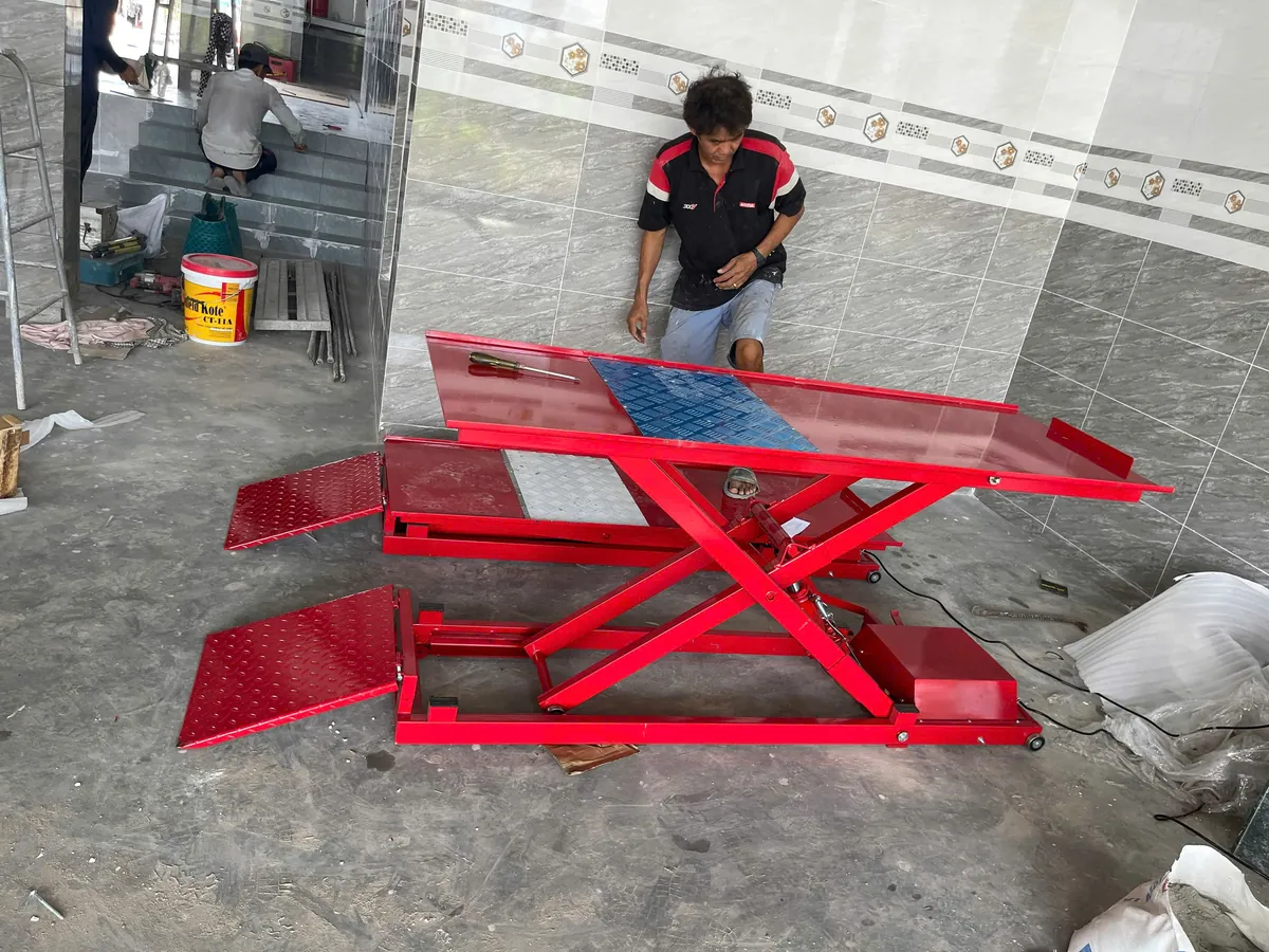 Bàn nâng xe máy điện và cơ Lộc Phát BXMDC được đặt trong không gian xưởng, sẵn sàng cho công việc sửa chữa.
