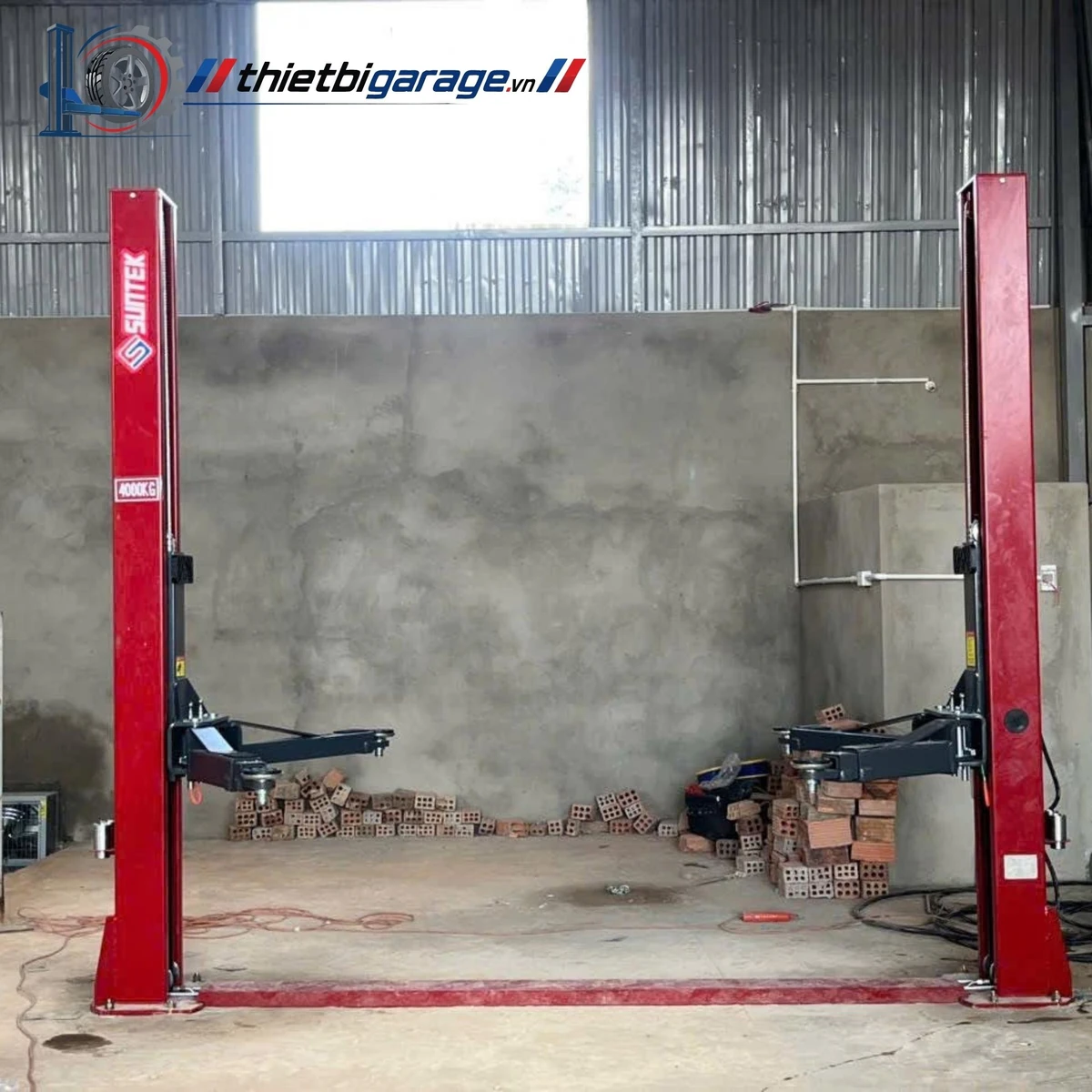 Cầu nâng ô tô 2 trụ Suntek 4000D màu đỏ, lắp đặt trong gara sửa chữa.