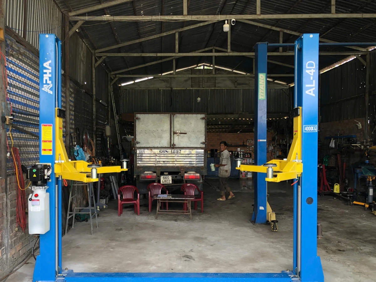 Cầu nâng ô tô 2 trụ Alpha AL-4D màu xanh vàng, trưng bày trong kho.