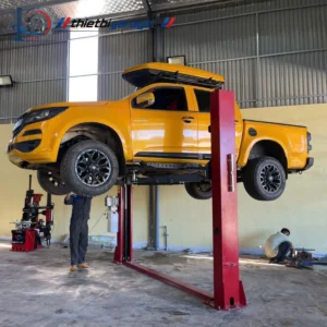 Cầu nâng ô tô 2 trụ Suntek 4000D đang nâng một chiếc xe bán tải màu vàng.