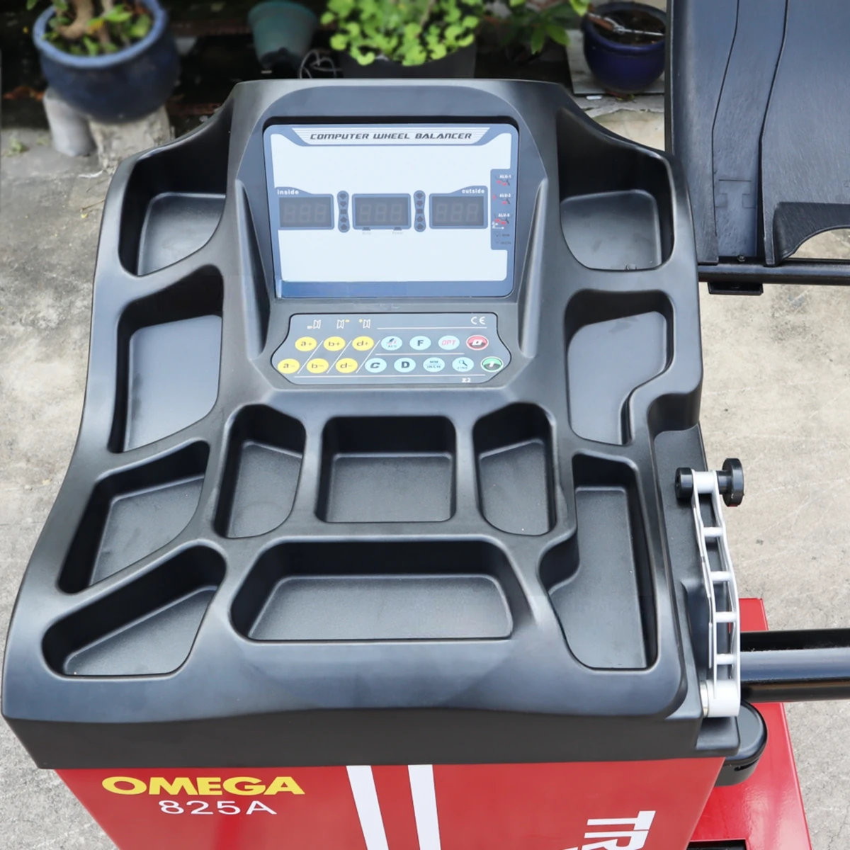 Máy cân bằng lốp ô tô OMEGA-825A, thiết bị Lộc Phát, đặt trong garage có bánh xe ô tô.