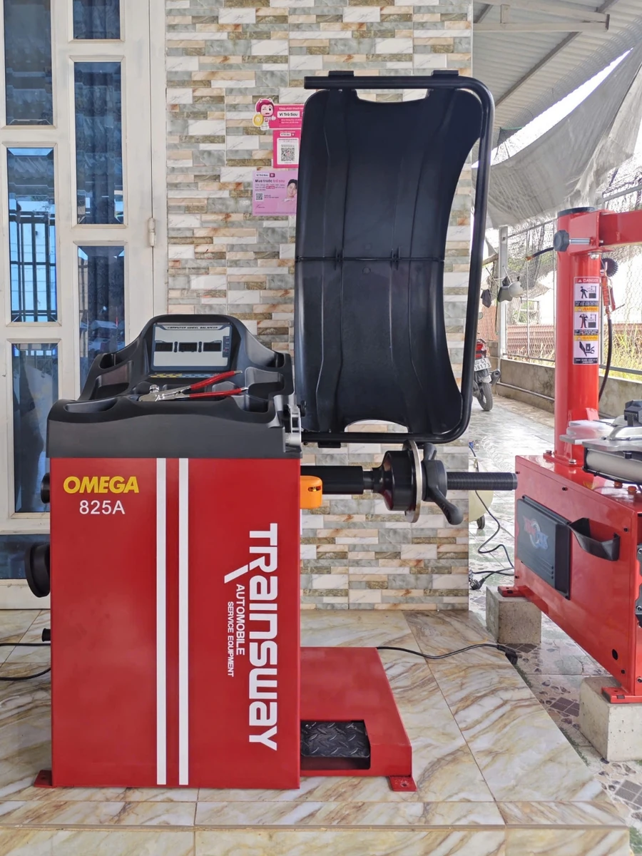Máy cân bằng lốp ô tô OMEGA-825A, thiết bị Lộc Phát, đặt trong garage.