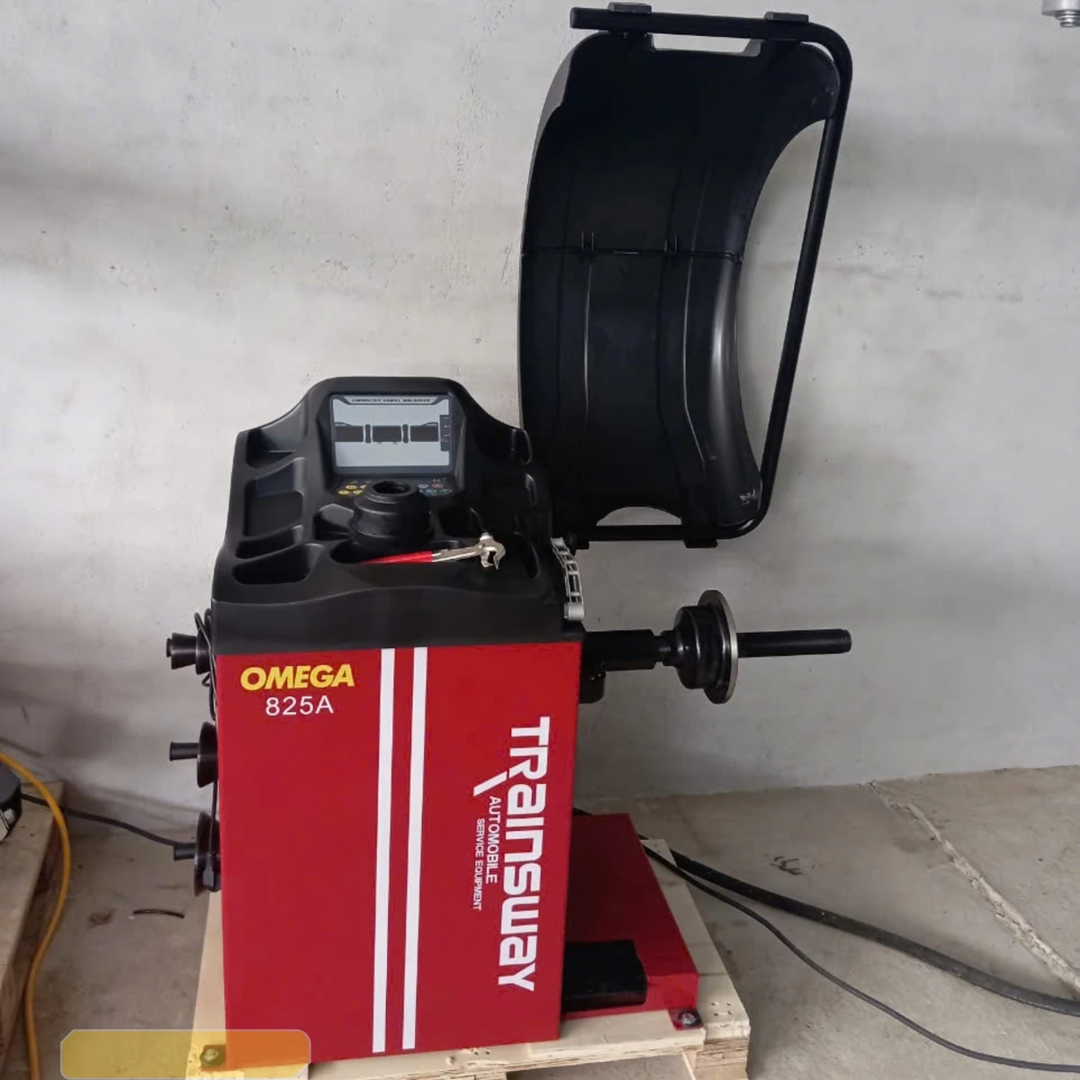 Máy cân bằng lốp ô tô OMEGA-825A màu đỏ, thiết bị Lộc Phát, đặt trên pallet gỗ.