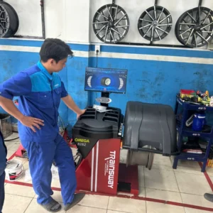 Kỹ thuật viên đang vận hành máy cân bằng lốp OMEGA TRAINSWAY 828Z chính hãng tại garage.