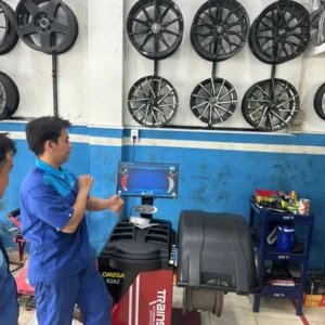 Kỹ thuật viên đang vận hành máy cân bằng lốp Omega Trainsway 828Z chính hãng tại garage.