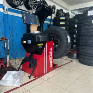Máy cân bằng lốp OMEGA TRAINSWAY 828Z chính hãng đang hoạt động tại garage, màn hình hiển thị thông số kỹ thuật.