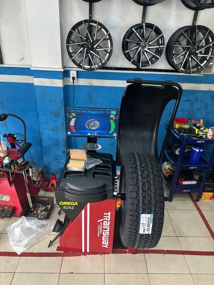 Máy cân bằng lốp OMEGA TRAINSWAY 828Z chính hãng Máy cân bằng lốp OMEGA TRAINSWAY 828Z chính hãng đang hoạt động tại garage, màn hình hiển thị thông số kỹ thuật.