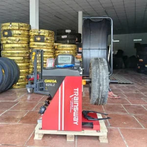 Máy cân bằng lốp ô tô Omega-Trainsway 825LZ Lộc Phát đang hoạt động tại garage, bánh xe được gắn trên trục máy.