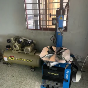 Máy tháo lốp Fly Speed FS-808 đặt cạnh máy nén khí LOPATEK trong không gian xưởng sửa chữa.