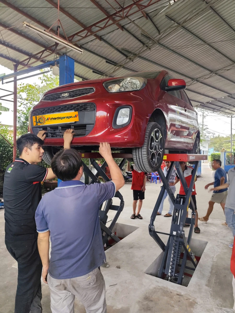 Cầu nâng ô tô Suntek 3500S kiểu xếp nâng thử tải xe Kia Morning Cầu nâng ô tô Suntek 3500S kiểu xếp đang nâng thử tải xe Kia Morning tại garage, kỹ thuật viên kiểm tra an toàn.