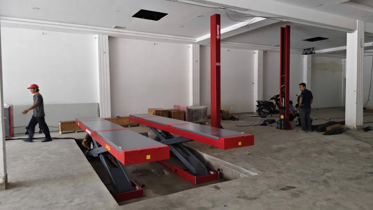 Đội ngũ kỹ thuật viên Lộc Phát đang lắp đặt cầu nâng cắt kéo tại garage sửa chữa.