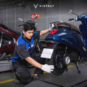 Kỹ thuật viên thao tác tháo hạ cụm động cơ motor đùm bánh sau xe máy điện trên bàn nâng