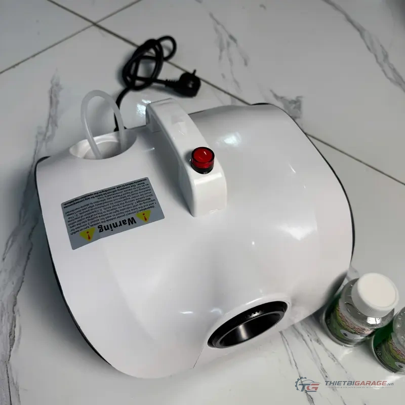 Máy khử mùi xe hơi QTA K2 góc nghiêng đặt cạnh chai dung dịch tinh dầu chuyên dụng